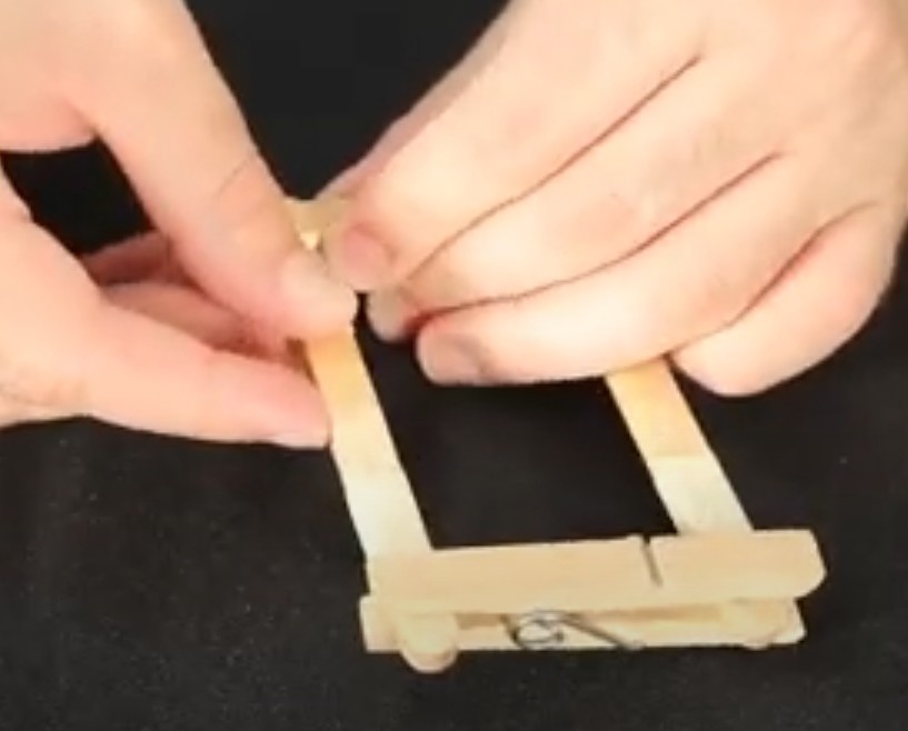 Encaixe um conjunto de palitos no outro lato do prendedor de roupas, sobrando 1cm de cada lado.