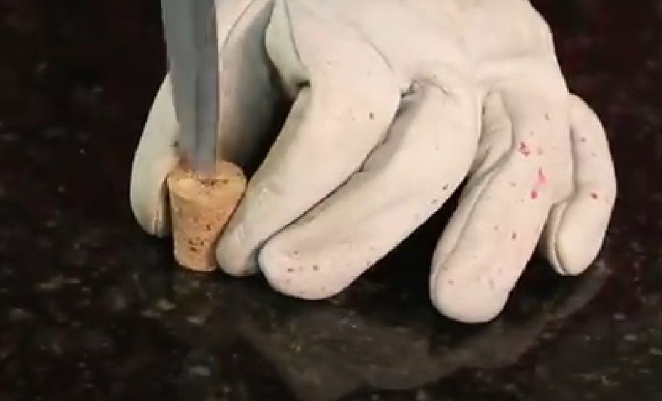 Segure a rolha, apoiada na mesa, na posição vertical. Posicione a ponta da faca no centro da rolha, coloque um pouco de pressão e gire para cavar e criar um buraco. Cuidado para não atravessar a rolha e nem a quebrar. NÃO SE ESQUEÇA DE UTILIZAR EPI.