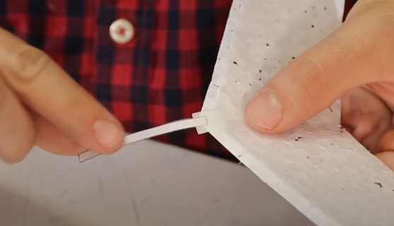 Por fim, para ajuste do peso, cole a última peça (front weight), com fita crepe, bem na ponta frontal do planador, deixando esta peça como se fosse uma língua, ou seja, você deve prender apenas uma ponta da peça ao planador deixando a maior parte para fora.