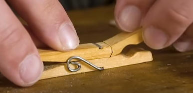 Serre uma das pontas do pregador de roupas (parte que segura a roupa), faça este corte próximo à mola do pregador mas deixe um pouco da madeira após a mola para que ela não se solte.