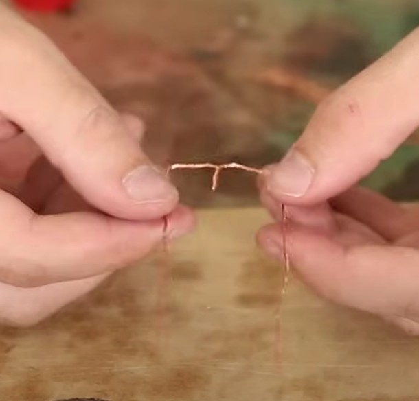 Dobre cada fio de uma maneira que forme um ângulo reto (90º) e os fios fiquem na mesma direção dos fios que enrolamos. No fim ficará igual um M com as laterais bem longas.