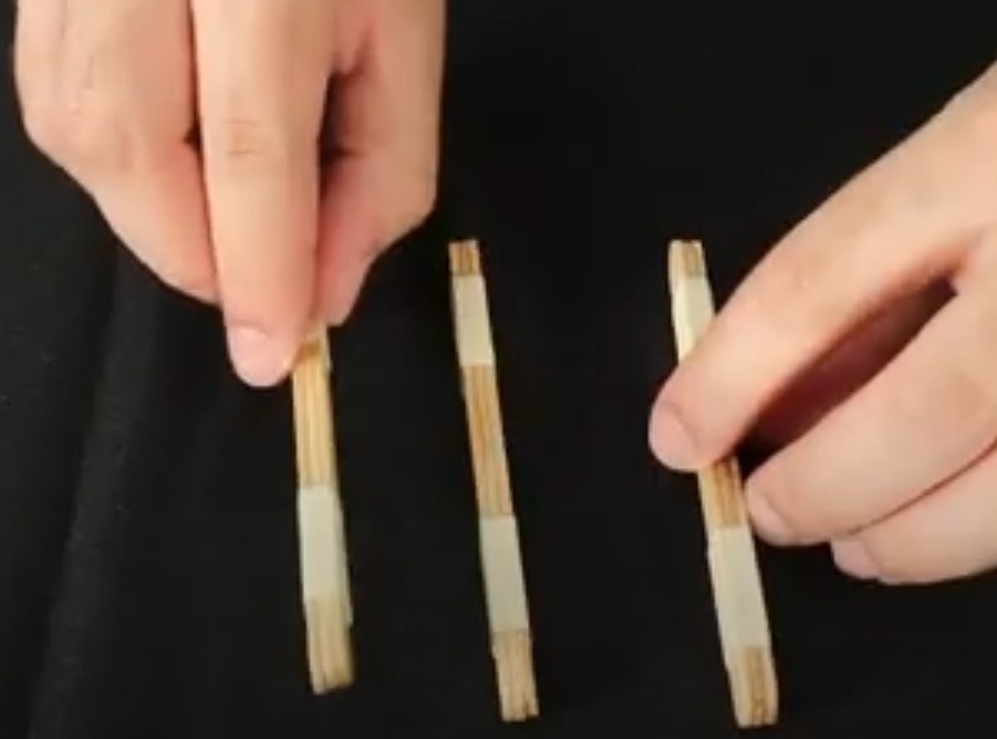 Separe 3 palitos de sorvete para juntar com fita crepe. Eles devem ser colados um atrás do outro para formar um conjunto de palitos, mantendo a altura e largura, mas mudando a espessura. Repita este processo mais duas vezes.