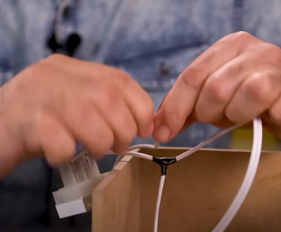 Enrole apenas uma ponta de um fio de 30cm em uma das aberturas de 0,5cm que foram feitas nos fios conectados no plug fêmea. Prenda bem e passe fita isolante.