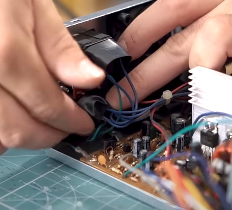 Para iniciar as conexões internas, precisamos isolar os terminais da entrada e saída de energia, afim de evitar qualquer acidente de 110v. Para isso coloque um pedaço de fita isolante nesses terminais enquanto trabalhamos com a fonte aberta. Ao final, poderemos remover esta fita.